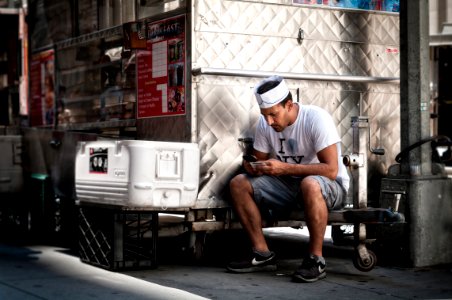 man in white shirt holding smartphone sitting near chest cooler photo