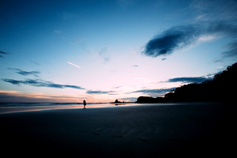 gray sand beside body of water during sunset