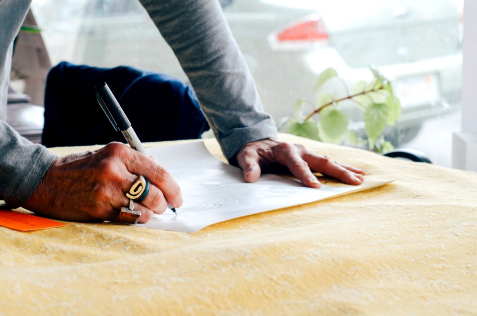 person writing on white plain paper on the table photography