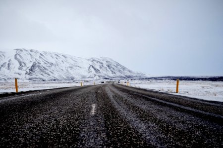 asphalt road near mountain filled with snow under cloudy sky photo