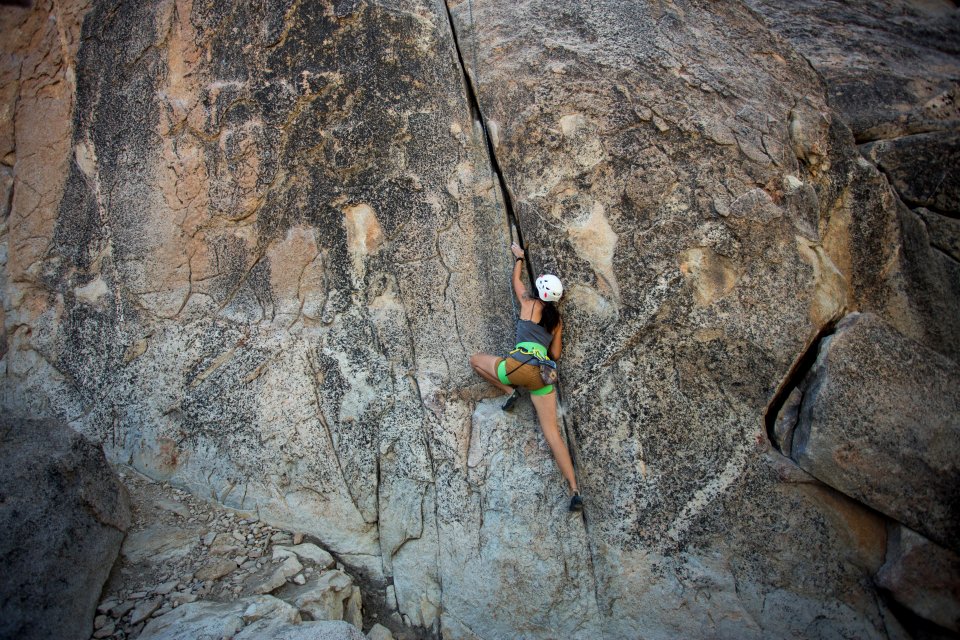 woman climbing on rock cliff during daytime