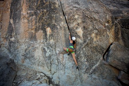 woman climbing on rock cliff during daytime