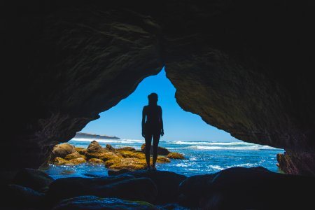 woman standing inside cave during daytime photo