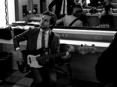 grayscale photography of man wearing suit holding guitar photo
