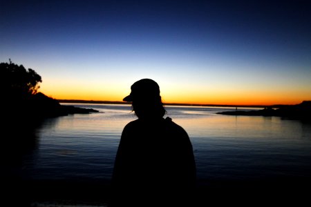 man standing near body of water silhouette photography photo