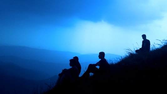 silhouette of men sitting on mountain