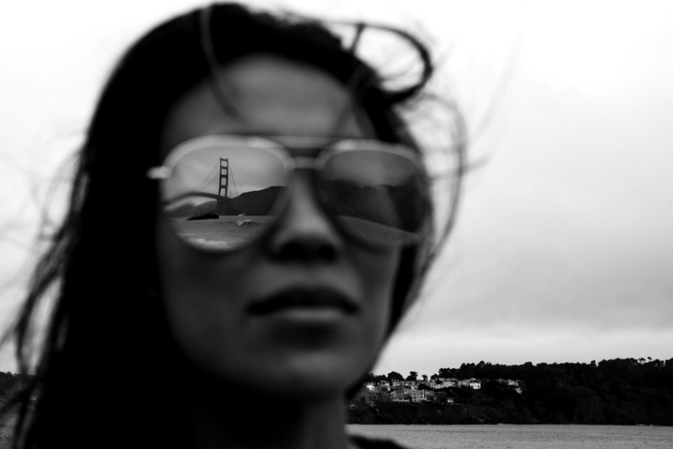Golden Gate Bridge reflecting on woman's sunglasses in grayscale photo