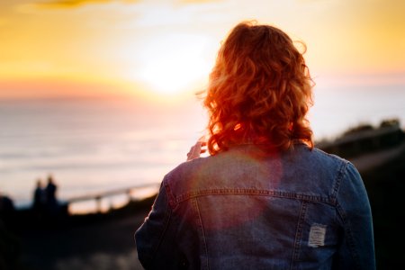 woman standing in front of ocean during sunset photo