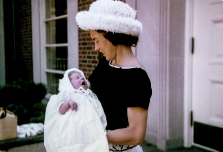 woman carrying baby standing near white wooden door