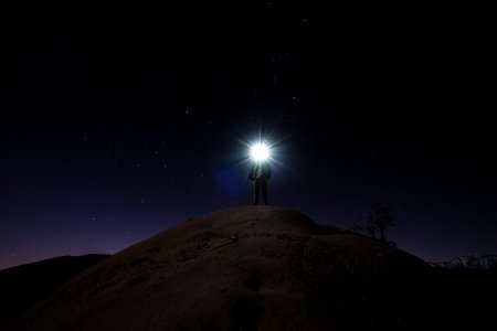 man standing on mountain white holding flashlight photo