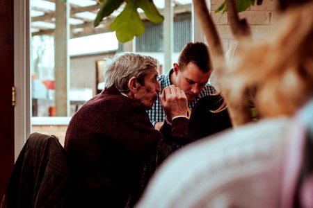 shallow focus photography of man sitting in front of the table while holding his hands together photo