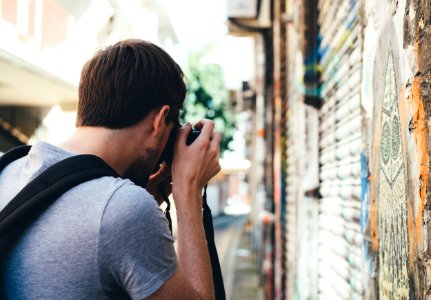man taking a photo of wall painting during daytime photo