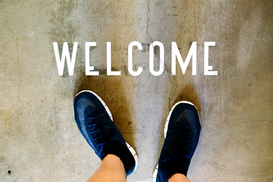 A person's feet in front of a welcome sign.
