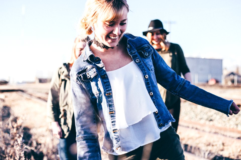 girl smiling wearing blue denim button-up jacket standing outdoor during daytime photo