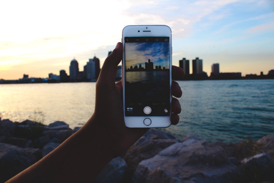 person taking picture of body of water and building