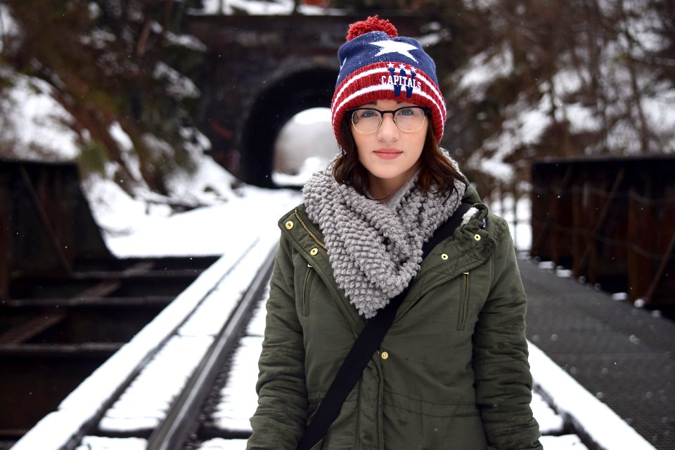 woman in green coat carrying black sling bag standing on railway photo