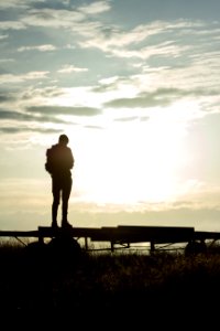 silhouette of man standing on wooden fence during sunset photo