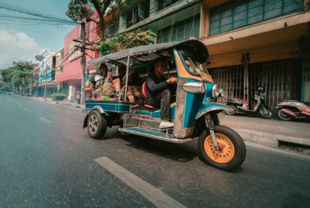 people riding in auto rickshaw near building photo