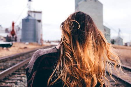 shallow focus photography of woman standing on train rail photo