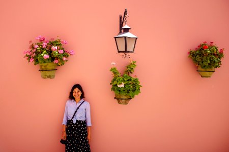 woman in white and black long sleeve shirt standing beside pink flower photo