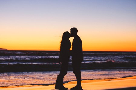 silhouette of couple sitting on seashore photo
