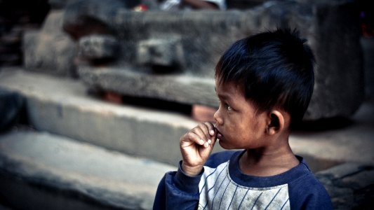 boy holding his lip standing on sidewalk photo