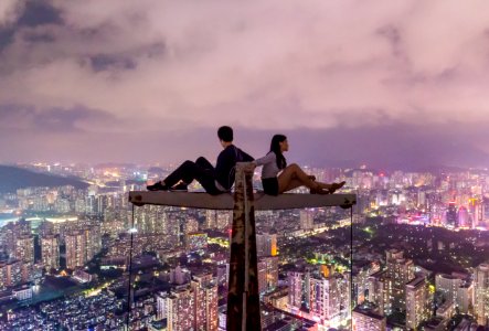 man and woman sitting on metal on top of high rise building photo