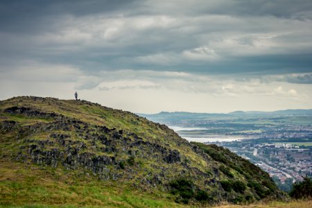 photography of person on mountain top with clouds as background