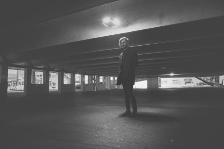 men standing under a building grey-scale photography