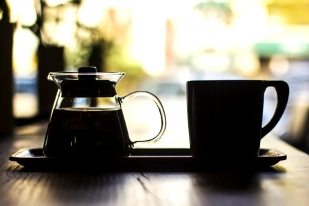 mug and coffee filled carafe on tray at the table photo
