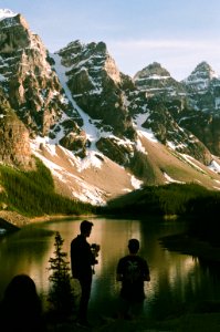 two men standing near body of water and mountain photo