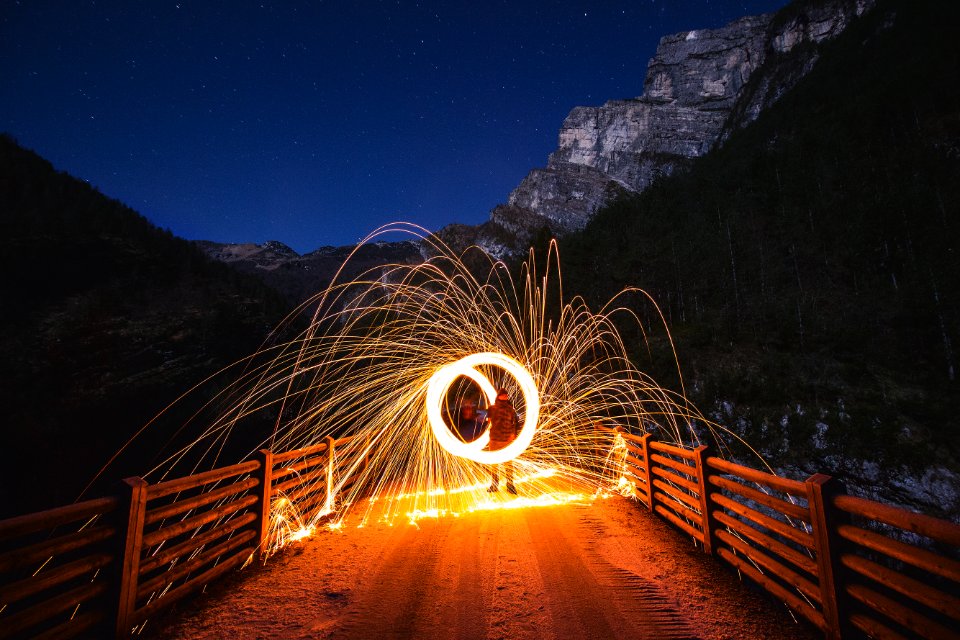 time-lapse photography of person holding steel wool on bridge