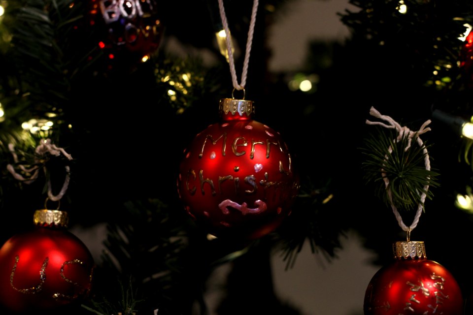 Red ornaments hanging from a Christmas tree.
