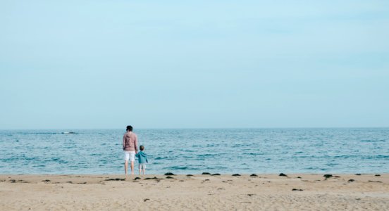 man and toddler standing on shore