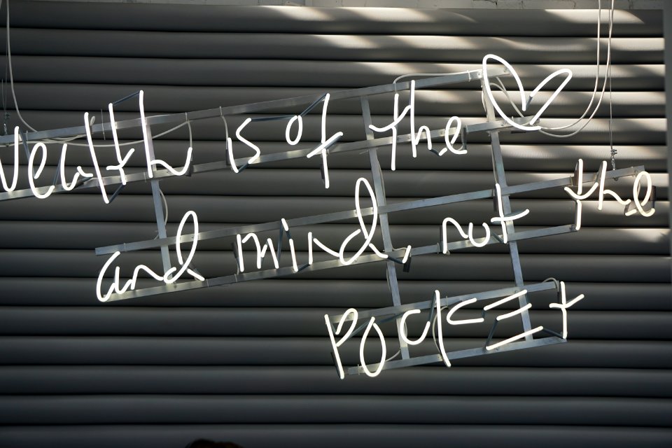 White paint on a garage door that says "Wealth is of the heart and mind not the pocket."
