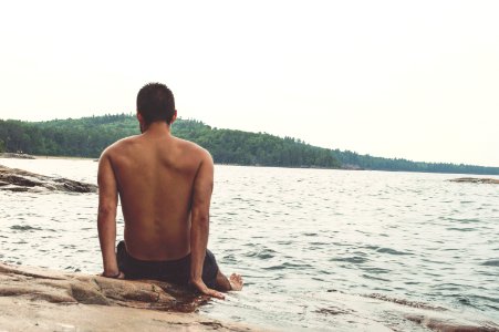 man wearing black shorts sitting on shoreline photo