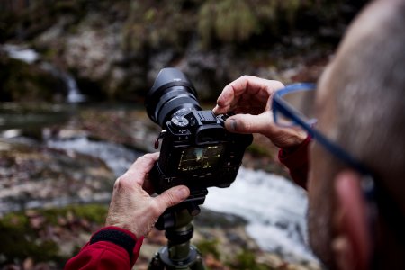 man taking photo of river using DSLR camera photo