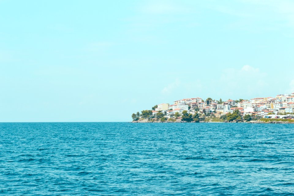body of water near buildings on cliff