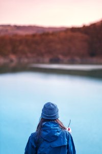 woman standing in front of lake selective focus photo photo