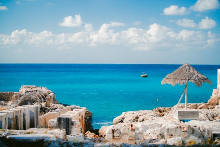 thatch parasol near ruins on island and sea at the distance during day
