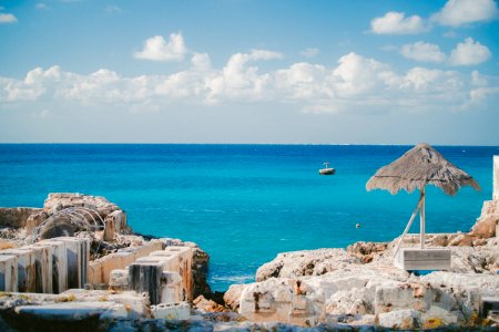 thatch parasol near ruins on island and sea at the distance during day photo