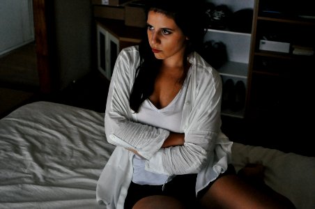 woman wearing white cardigan sitting on bed photo
