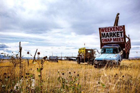 blue and white car on brown grass field under white clouds during daytime photo