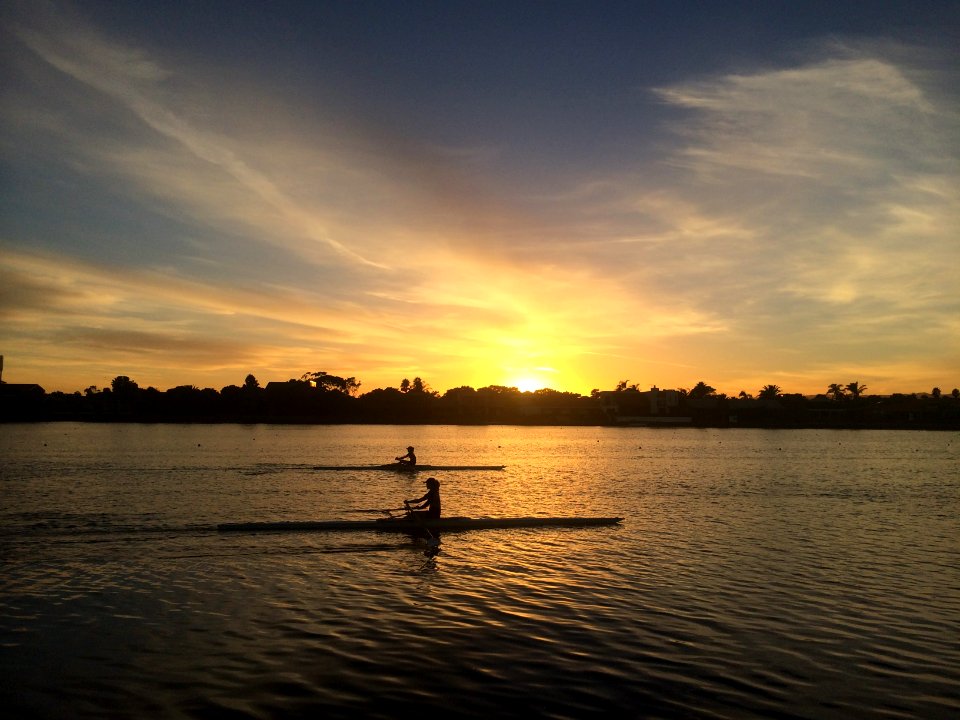 two people silhouette on body of water during golden hour