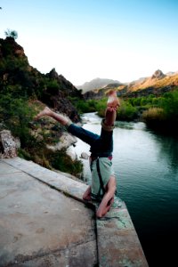 person in gray top doing headstand in front of body of water photo