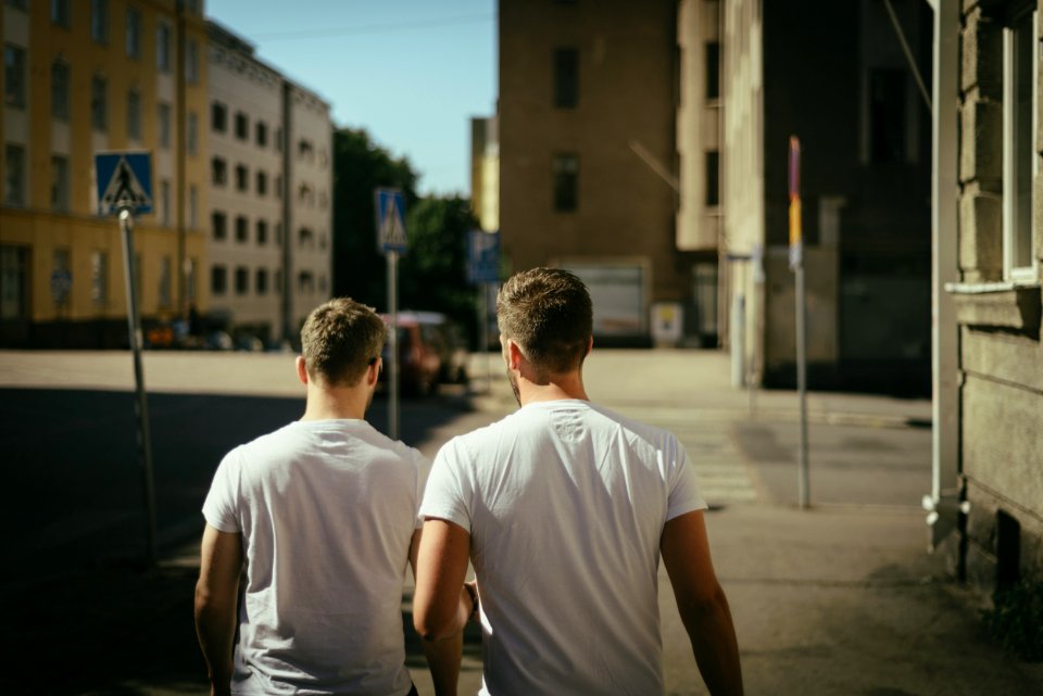 Two men in white t-shirts walk away down a city street