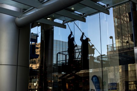 utility man standing in scissor platform cleaning glass window photo