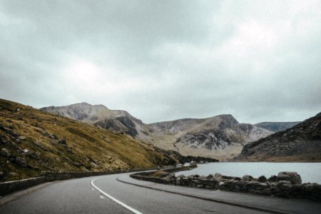 landscape photography of road near mountain under cloudy sky photo