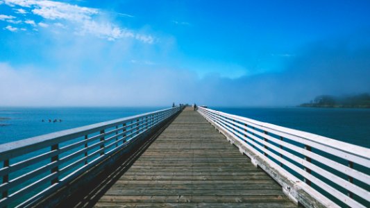gray and white wooden sea dock under blue and white sky at daytime photo