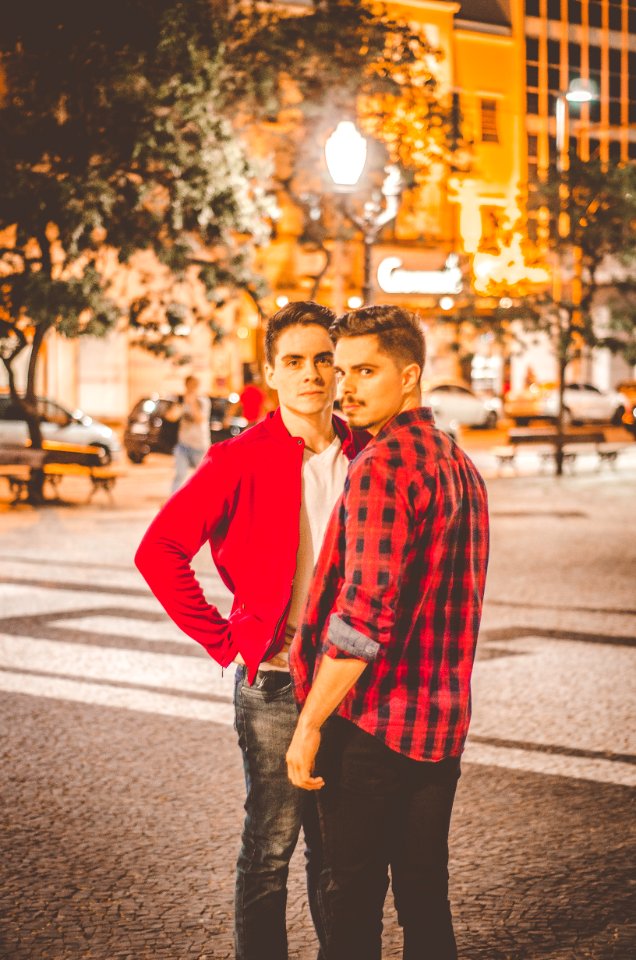 Two young men standing close together at night in a city square